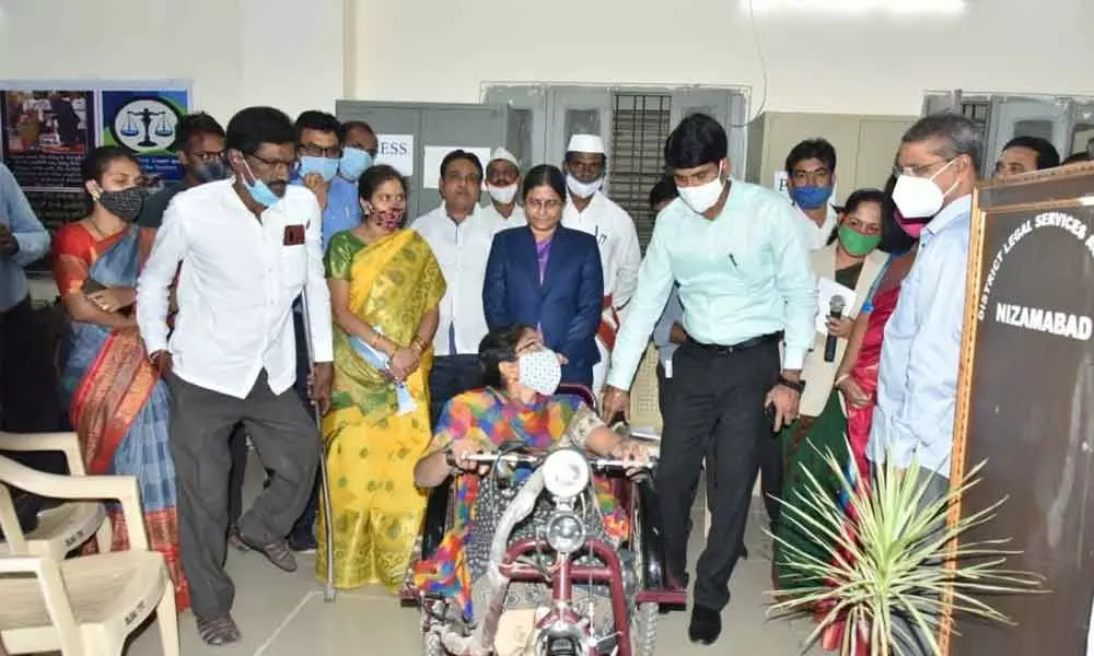District Collector C Narayana Reddy explaining driving precautions to a disabled woman after giving her tricycle moped in Nizamabad
