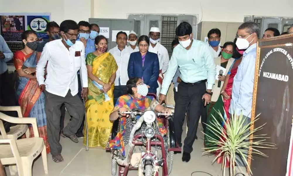 District Collector C Narayana Reddy explaining driving precautions to a disabled woman after giving her tricycle moped in Nizamabad on Friday