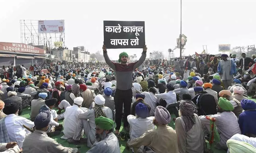 A farmer holds a placard at Singhu border during ‘Delhi Chalo’ protest march