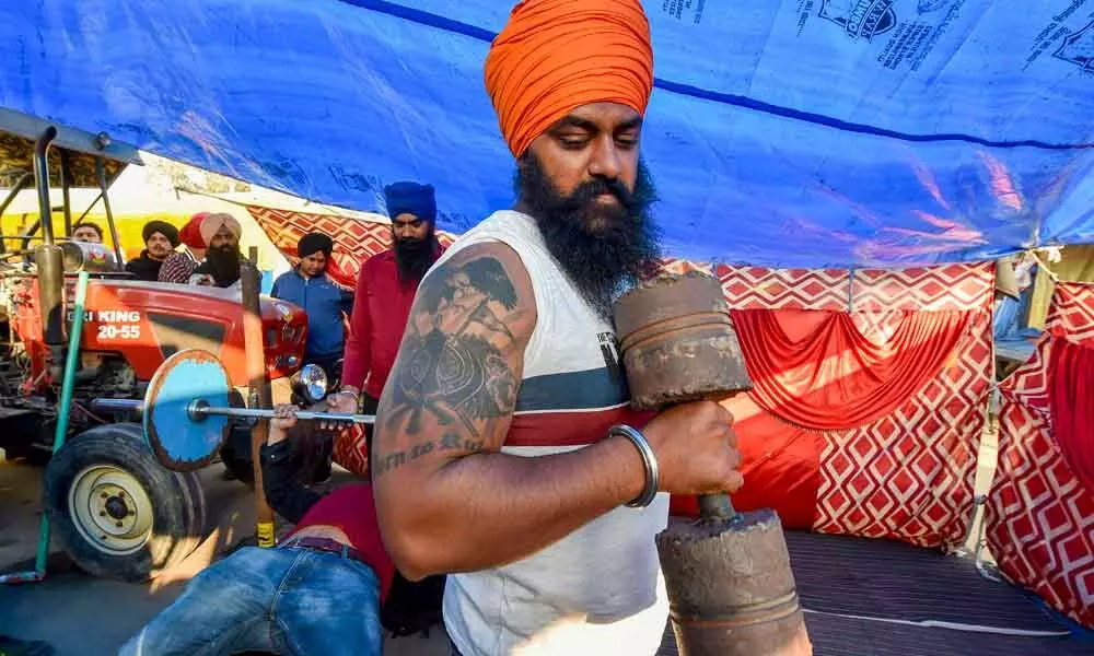 A farmer exercises at Singhu border during their sit-in protest against the Centres farm reform laws, in New Delhi on Monday