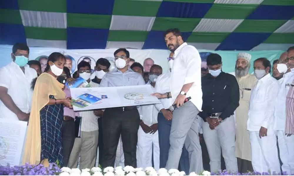 Minister Dr P Anil Kumar Yadav handing over the house site patta to a beneficiary at a programme in Nellore on Friday