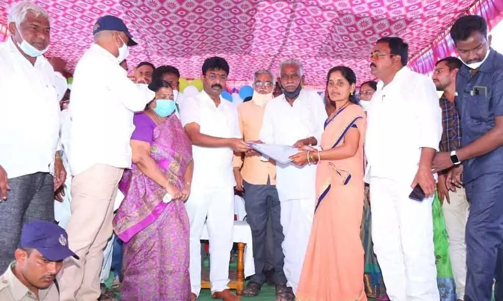 Minister Audimulapu Suresh distributing house site patta to a beneficiary on Monday