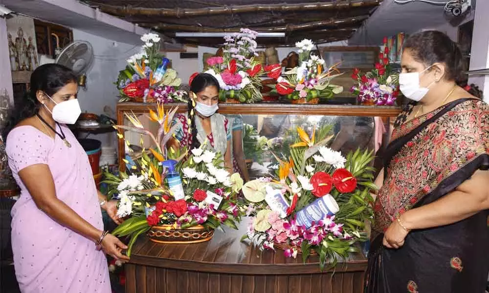 Women curiously look at the Corona flower basket in Tirupati ahead of New Year.
