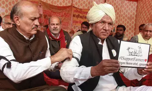 Farmers tie black ribbons on the arms of each other to observe New Years Day as Black Day, during their protest against the new farm laws, in Gurugram on Friday