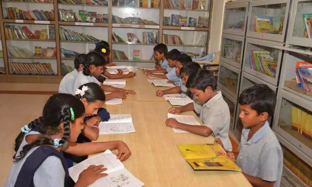 Children reading books at a school library in Anantapur