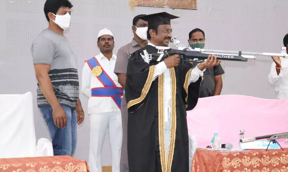 Mayor Gunda Prakash Rao handling a demo shooting rifle at the general body meeting of the GWMC in Warangal on Saturday