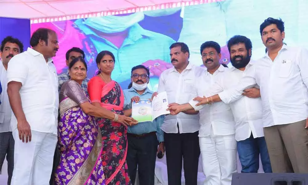 Ministers B Satyanarayana, A Suresh, MLA TJR Sudhakar Babu and others presenting a housing plot document to a beneficiary in Chimakurthy