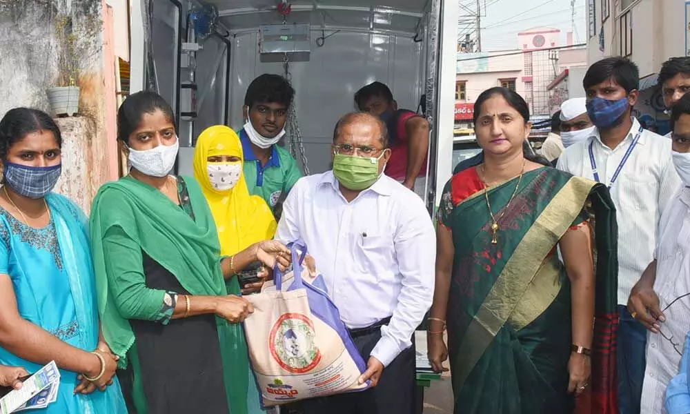 Krishna district Collector Md Imtiaz handing over rice bag to a beneficiary in Vijayawada on Monday