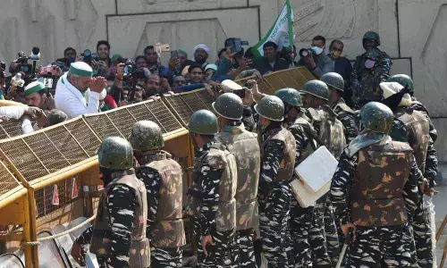 BKU leader Rakesh Tikait gestures towards security personnel who had blocked farmers movement during their protest against Centres farm laws, at Ghazipur border in New Delhi on Saturday