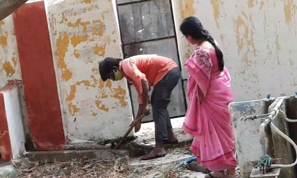 Maths teacher cleaning the front yard of a toilet in ZPH School in Godishala village
