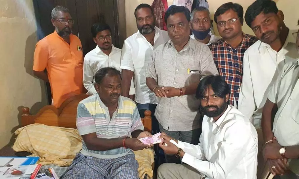 Social worker Pawan Kumar Yadav handing over financial assistance of Rs 20,000 to theatre artist Janardhan at his house in Tatikonda village on Tuesday