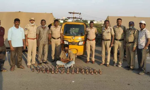 SEB Circle Inspector N Lakshmi Durgaiah with seized liquor bottles at Panchalingala border check post on Saturday.