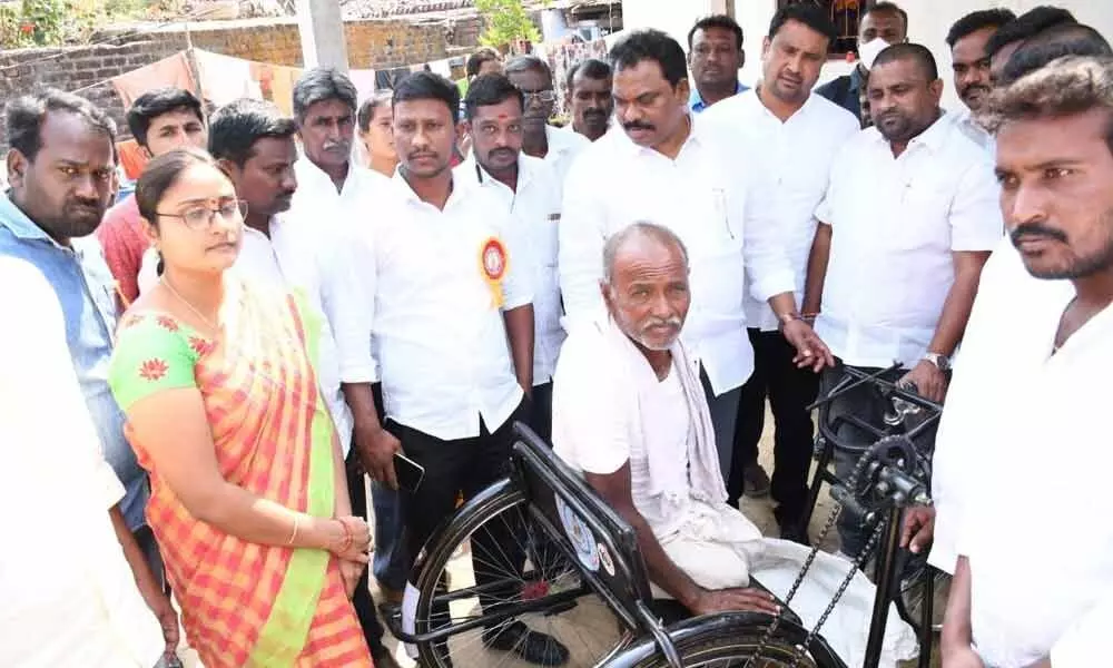 MLA S Ravi Shankar handing over tricycle to disabled farmer B Anjaiah at Gumlapur village on Sunday