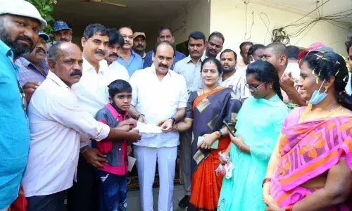 Minister Balineni Srinivasa Reddy and his wife Sachidevi handing over the CMRF cheque to Chaitanya and his parents in Ongole on Sunday