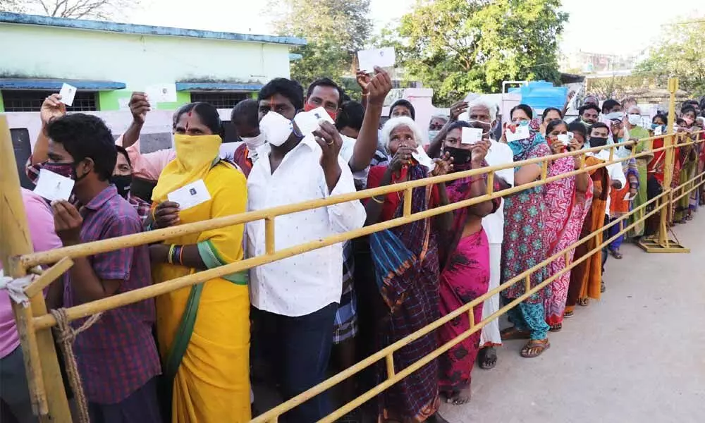 Voters stand in a queue at a polling station at Thimminaidupalem in Tirupati on Wednesday