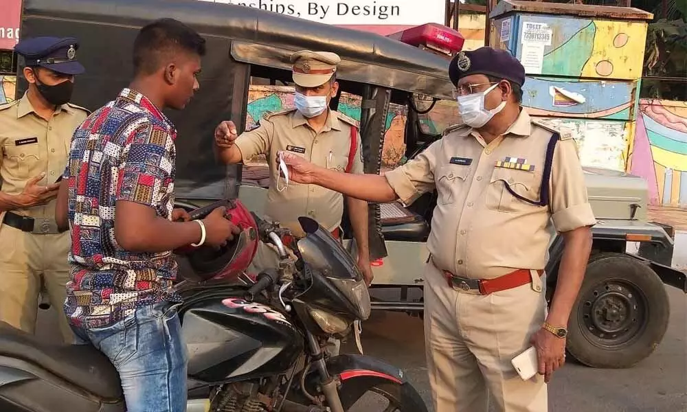 Deputy Commissioner of Police (Crimes) V Suresh Babu distributing masks to a motorist in Visakhapatnam