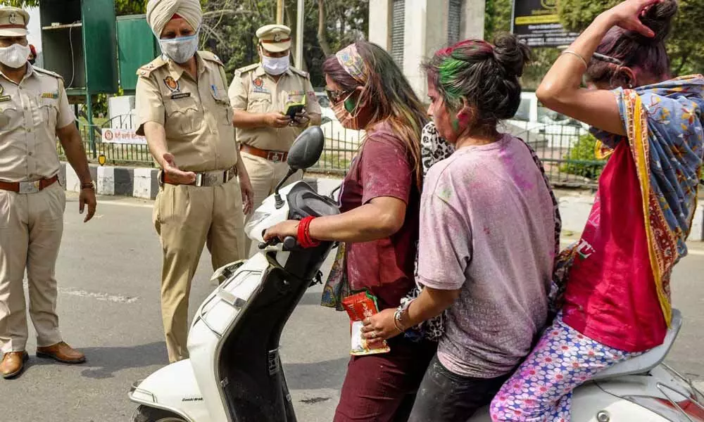 Police stop commuters for violating traffic rules, during the Holi festival in Patiala on Monday
