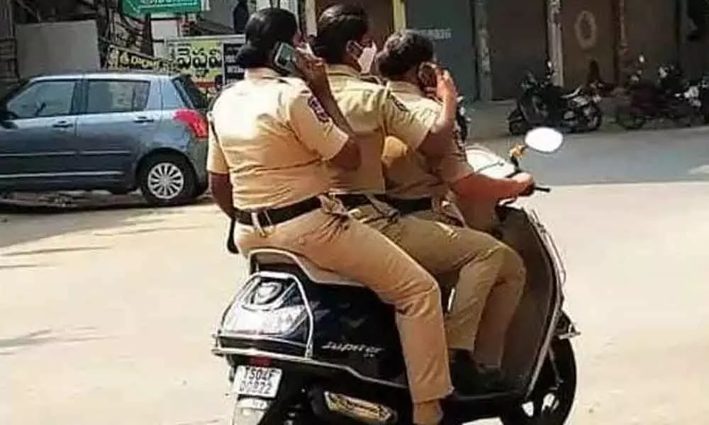 Three women constables riding a bike without helmet and talking on mobile phone in Khammam