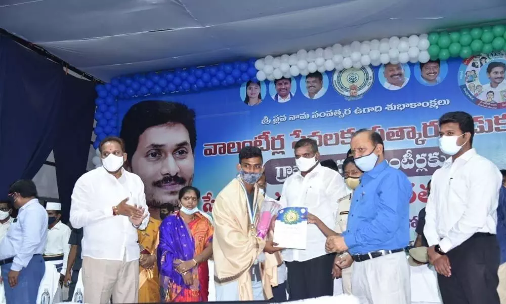 Minister Botcha Satyanarayana presenting award to volunteer at Vizianagaram