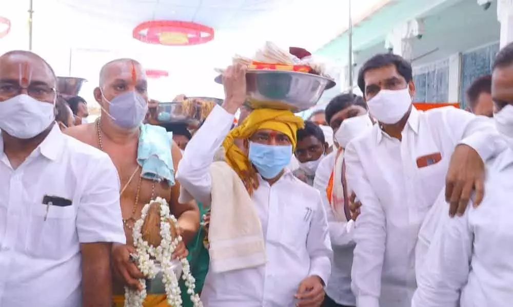 Health Minister Eatala Rajender carrying silk clothes and Talambralu to offer to the presiding deity at Sita Ramchandra Swamy temple in Yellanthakunta village