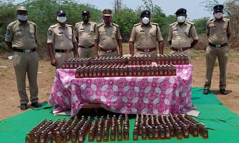 Special Enforcement Bureau police with seized liquor bottles in Nandigama on Friday