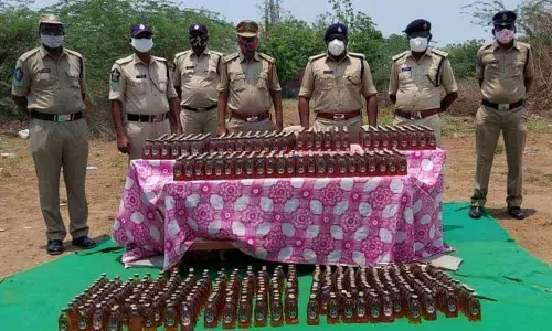 Special Enforcement Bureau police with seized liquor bottles in Nandigama on Friday