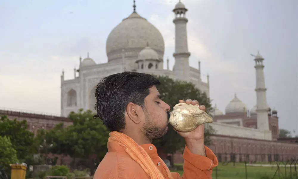 A man blows a conch as part of an exercise to strengthen his lungs, near Taj Mahal in Agra on Monday