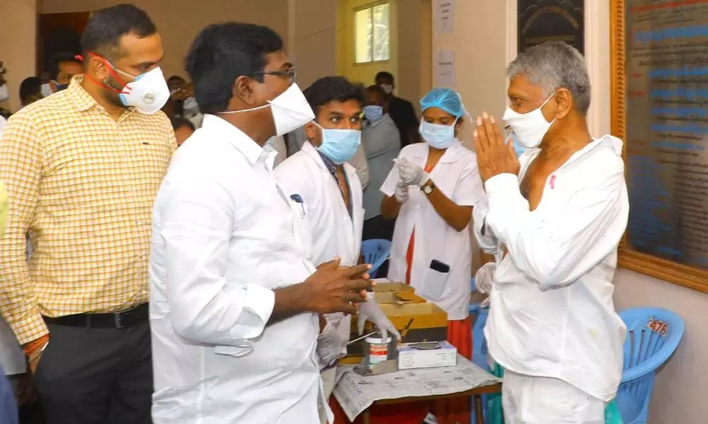 Transport Minister P Ajay Kumar interacting with a person, who is taking second dose of Covid vaccine at a vaccination centre in Khammam on Tuesday