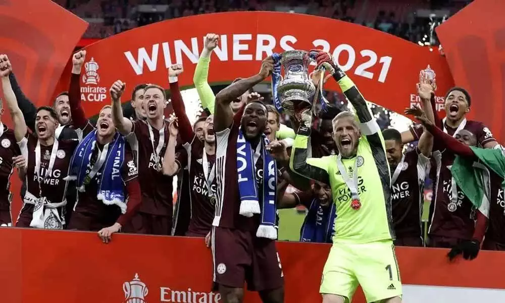 Leicester Citys goalkeeper Kasper Schmeichel (right) and Wes Morgan hold the trophy aloft at the end of the FA Cup final soccer match against Chelsea at Wembley Stadium in London, England late on Saturday. Leicester won the match 1-0