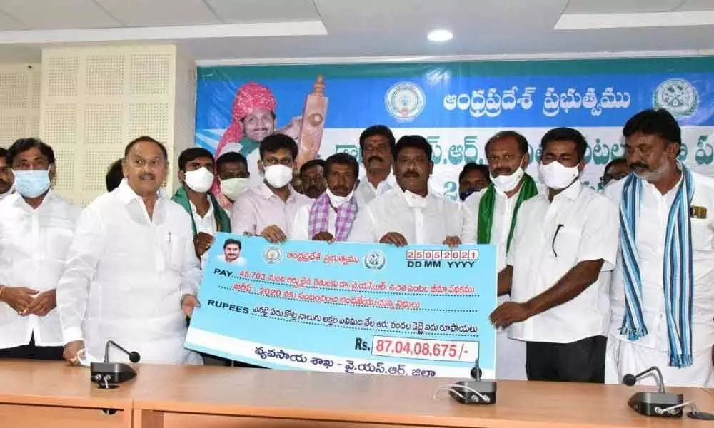 Government Chief Whip G Srikanth Reddy and Collector Ch Harikiran handing over a cheque to farmers under Dr YSR Free Crop Insurance Scheme in Kadapa on Tuesday