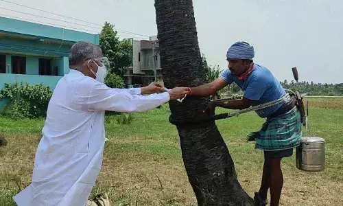 Minister Chelluboina Venu Gopala Krishna handing over facemask to a toddy-tapper at Ramachandrapuram  in East Godavari district on Thursday