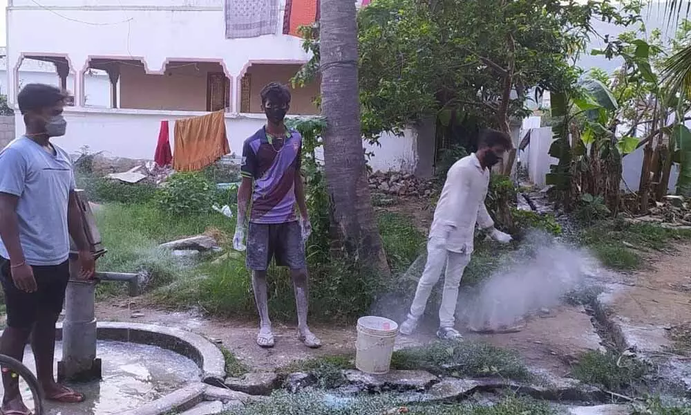 Ganesh youth association members spraying bleaching powder at Apparayudupalem village in Visakhapatnam on Friday