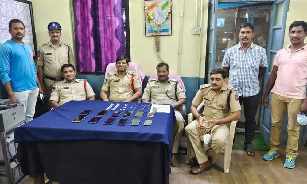 RPF and GRP Inspectors K Madhusudhan and Indrasen Reddy displaying the seized mobile and gold ornaments at Khammam railway station on Saturday