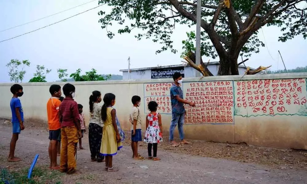Students reading alphabets and numbers written on the wall in Mesaramguda village under Thirayani mandal in Asifabad district