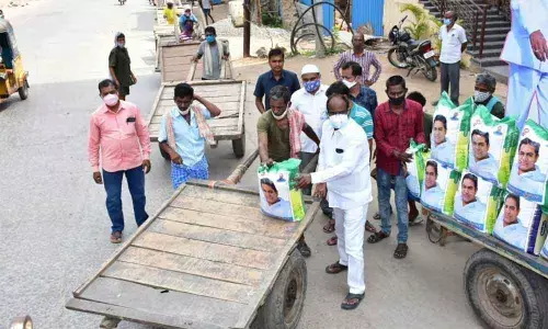 TRS leader Rajanala Srihari distributing rice bags to Hamalis in Warangal on Monday