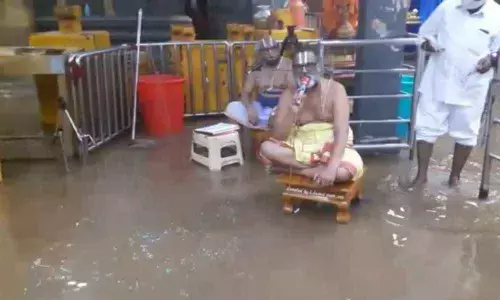 Priests performing Suprabhata Seva in rainwater that entered Balalayam of Yadadri on Thursday