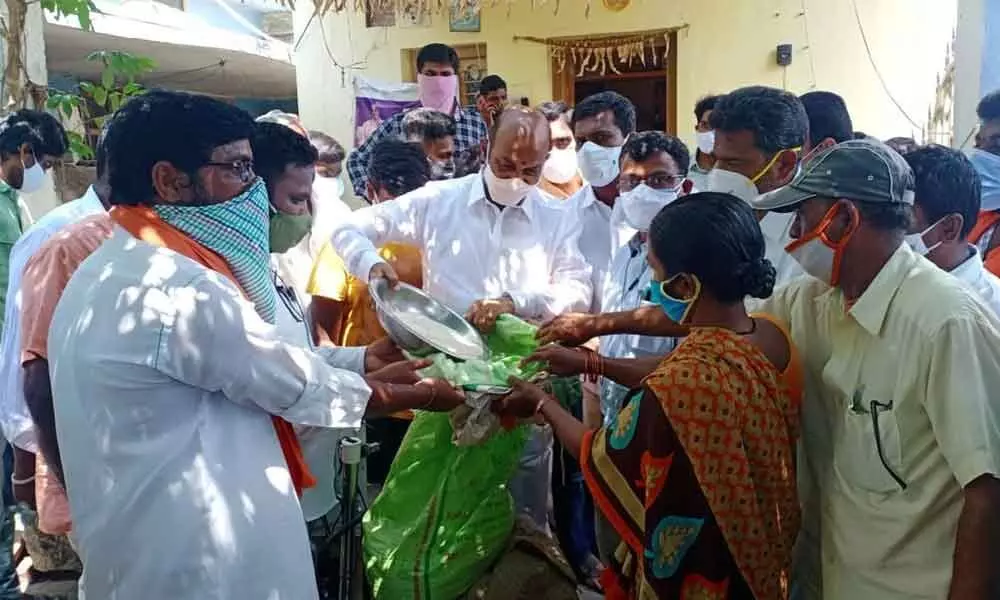 BJP State president B Sanjay Kumar distributing rice to a poor woman at Pedda Papayyapalli on Monday