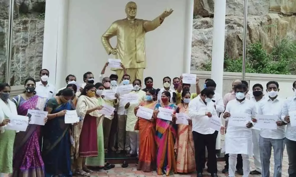 TDP leaders staging a protest with placards at NTR statue in Visakhapatnam on Friday