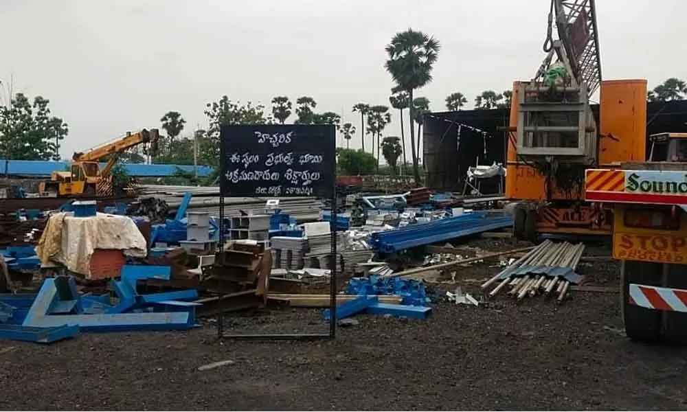 Revenue officials placing a warning board at Palla Srinivasa Rao’s property in Visakhapatnam on Sunday
