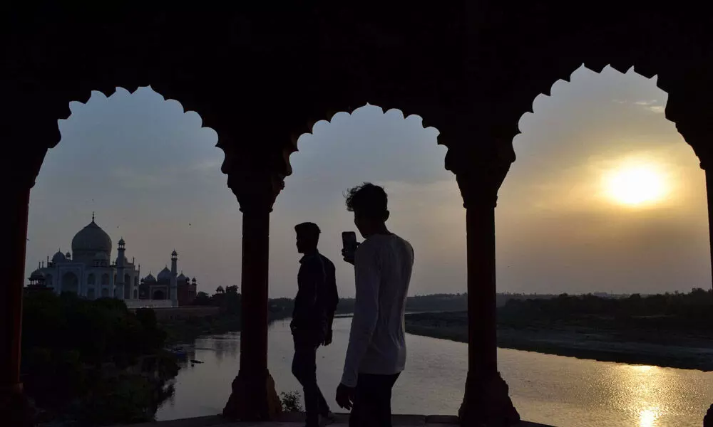 People take photographs of the historic Taj Mahal during sunset, ahead of its reopening in Agra on Monday