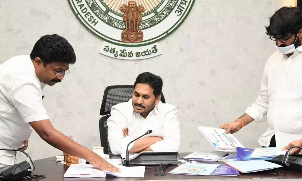 Education Minister A Suresh shows the dictionaries to be distributed to students under Vidya Kanuka to Chief Minister Y S Jagan Mohan Reddy, during a review on education at Tadepalli on Thursday