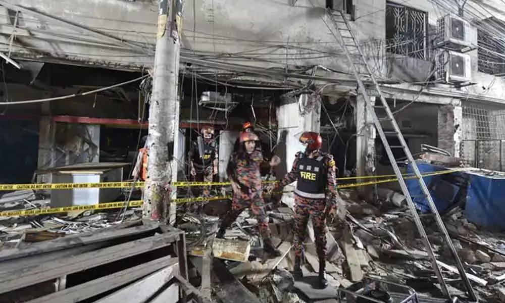 Firefighters rescuers inspect the scene after a suspected gas explosion in Bangladesh