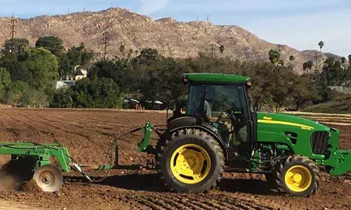 Green tractor with rotortiller at a farm in Anantapur
