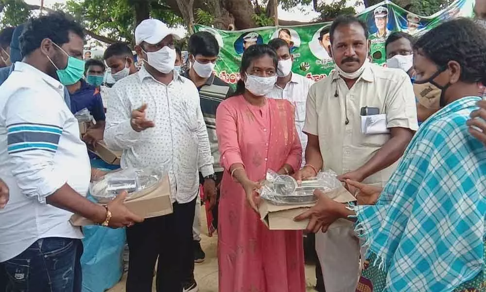 SP B Rajakumari distributing saris and utensils to tribals at Tadiputti village in Vizianagaram district on Saturday