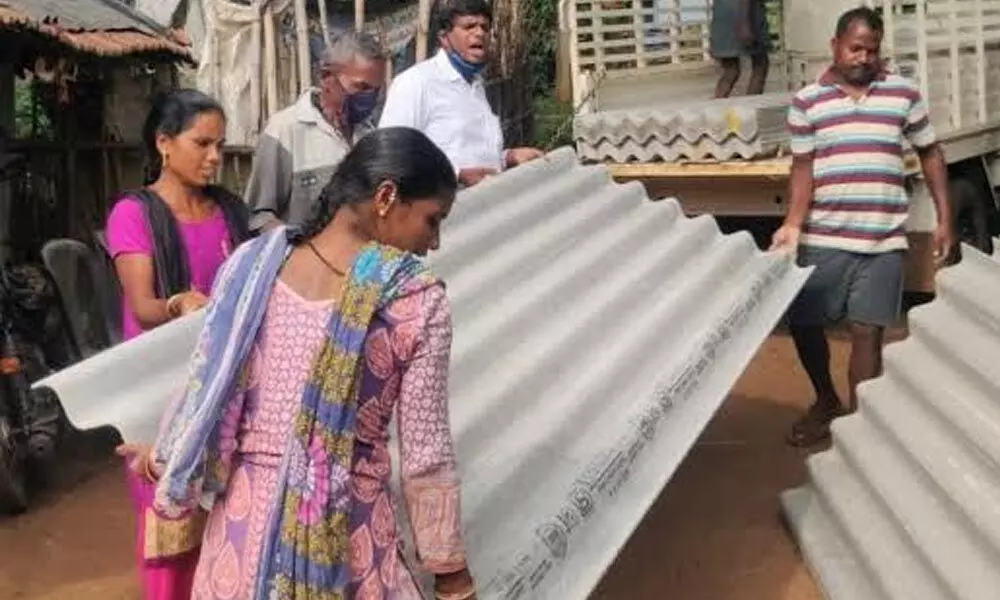 Sri Sathya Sai Seva Organisation members distributing asbestos sheets to a tribal family in Paderu on Tuesday