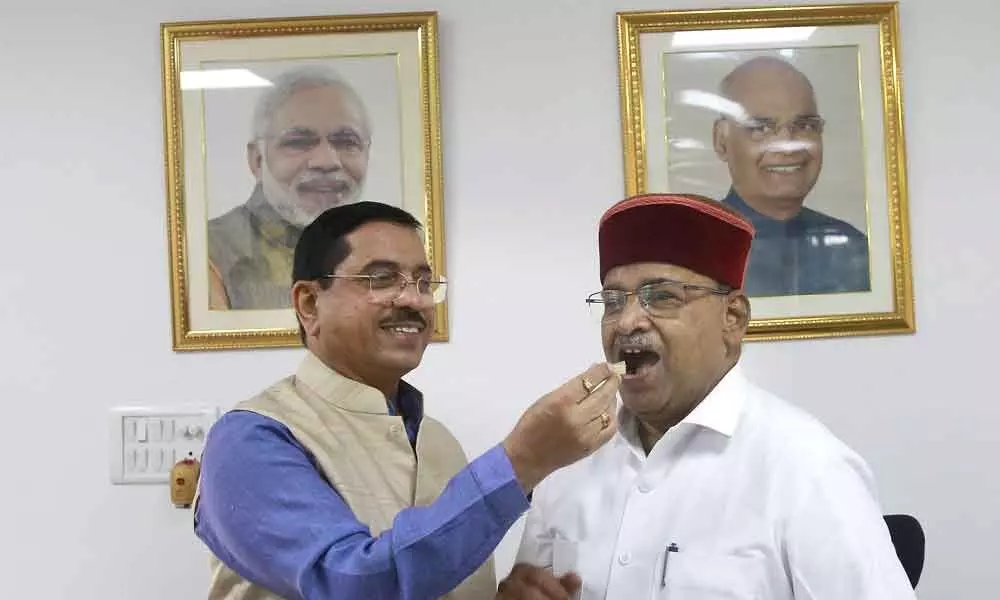 Union Minister Pralhad Joshi offers sweets to Social Justice Minister Thawarchand Gehlot after he was appointed as the Governor of Karnataka, in New Delhi on Tuesday