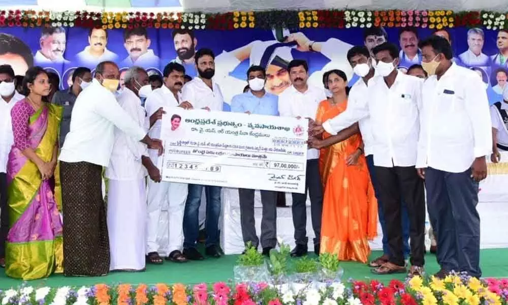 Ministers Perni Nani and Kodali Nani distributing cheques to farmers to mark the YSR Rythu Dinotsavam in Pedana on Thursday