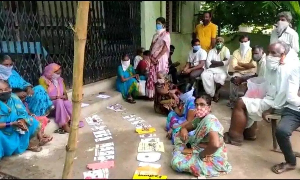 People keep their Aadhaar cards in a queue to receive Covid vaccine at Raikal mandal headquarters in Jagtial district on Wednesday