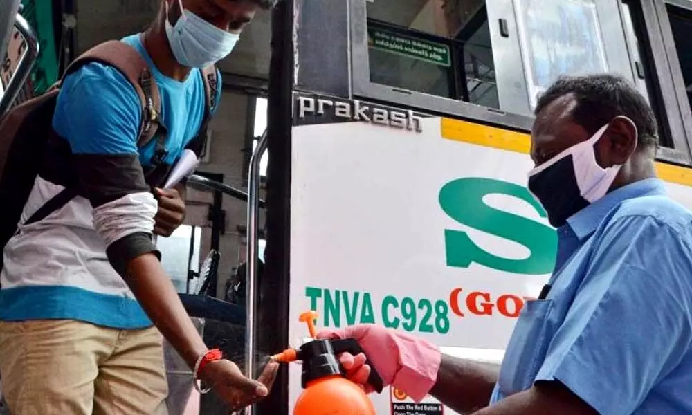 bus conductor giving hand sanitizer to a passenger at Tirunelveli New bus stand. (Photo | EPS/ V Karthik Alagu)