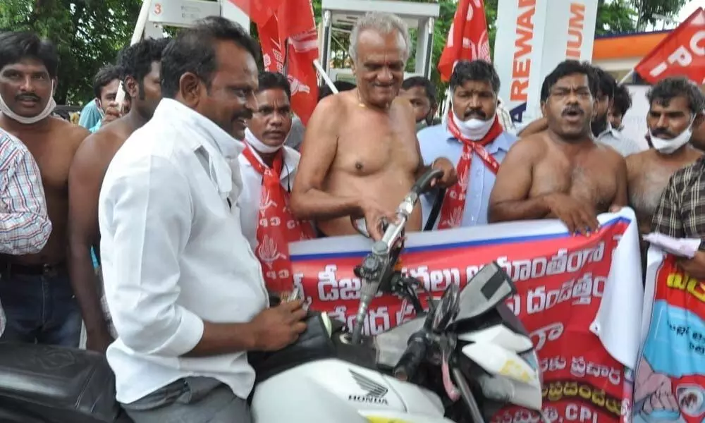 CPI national secretary K Narayana filling petrol in a bike at a petrol bunk during their half-naked protest in Tirupati on Sunday